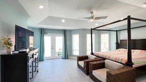 Um quarto espaçoso com cama de dossel, televisão, escrivaninha e área de estar.
