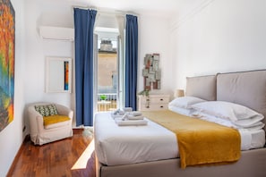Habitación de hotel con cama, una silla, mesita de noche, ventana con cortinas y aire acondicionado.