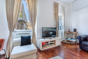 Una sala de estar con televisión, sofá y chimenea.