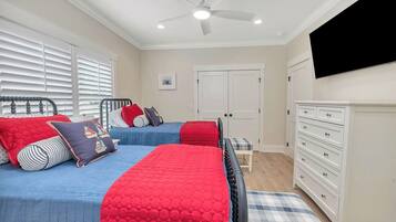 A bedroom with two beds, a ceiling fan, a TV, and a dresser.