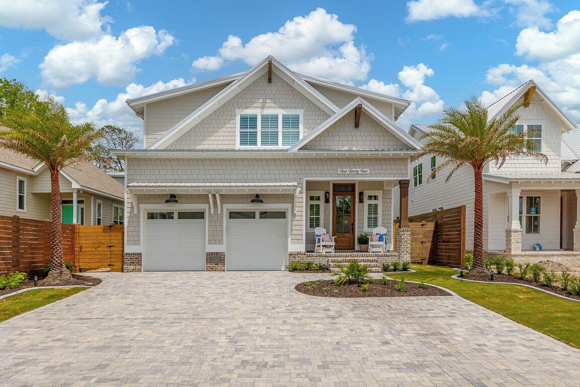 A two-story house with a front garage, a covered porch, and a landscaped driveway.
