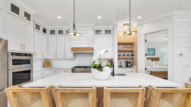 A modern kitchen with white cabinetry, a central island with seating, and stainless steel appliances.