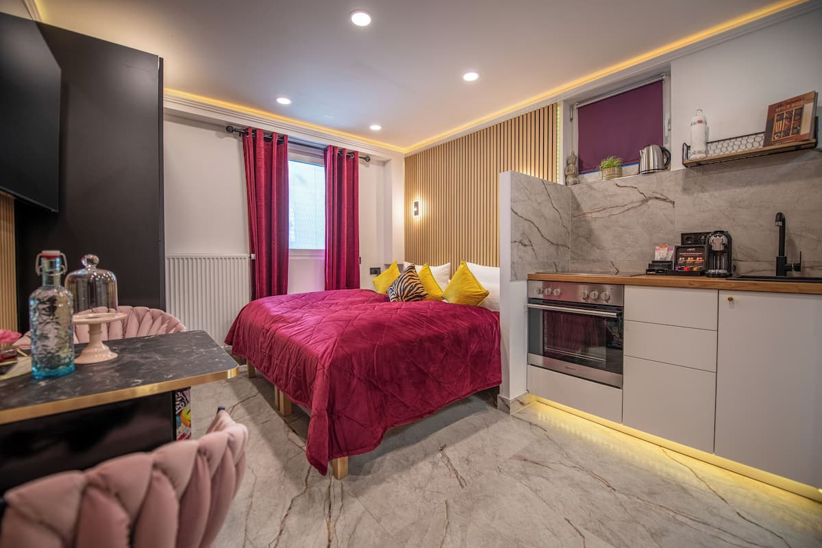 A modern bedroom with a large bed, a dining table, and a kitchen area.