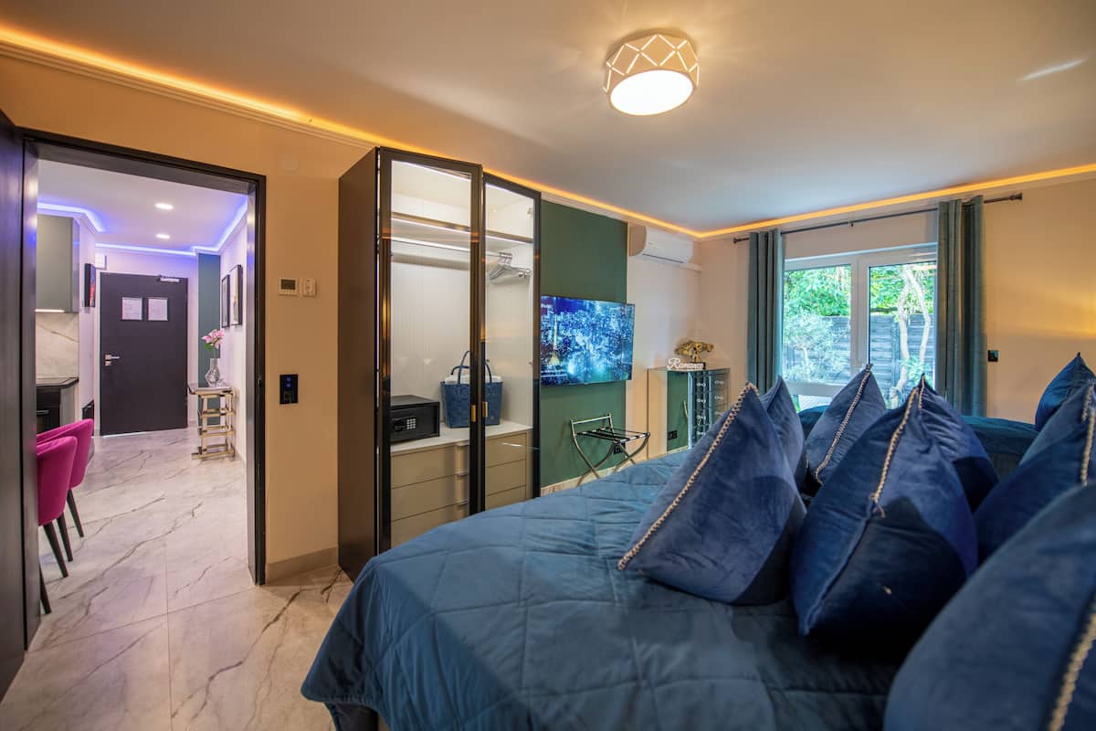 A modern bedroom with a large bed, a TV, and a view of the outdoors.