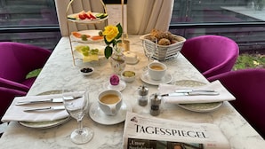A dining table set with plates, cutlery, glasses, and a newspaper. - Villa Tropicana (Teltow)