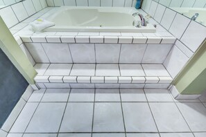 Bathroom features a large bathtub and white tiled flooring.