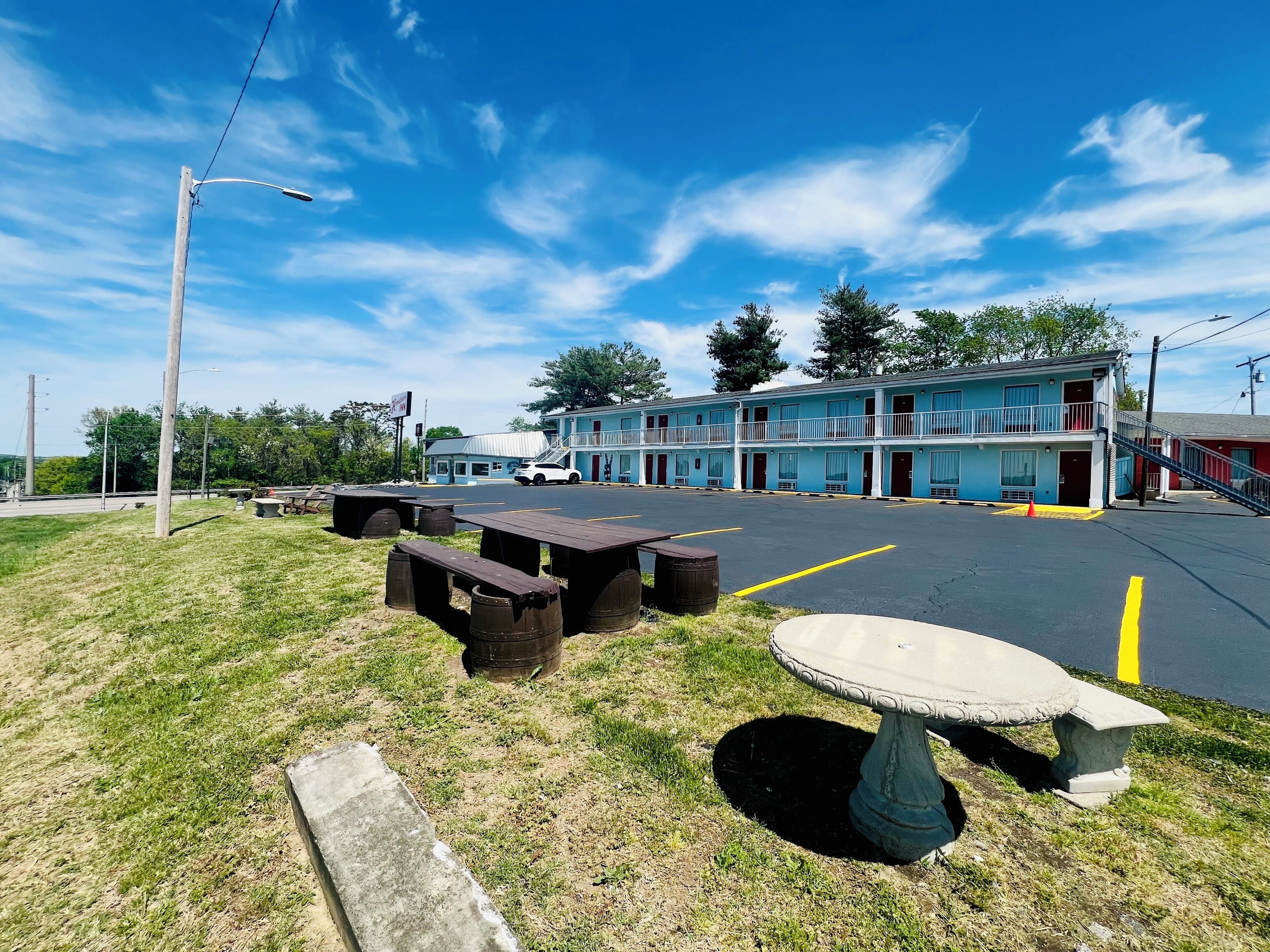 A motel with a two-story building, outdoor seating, and a parking lot.