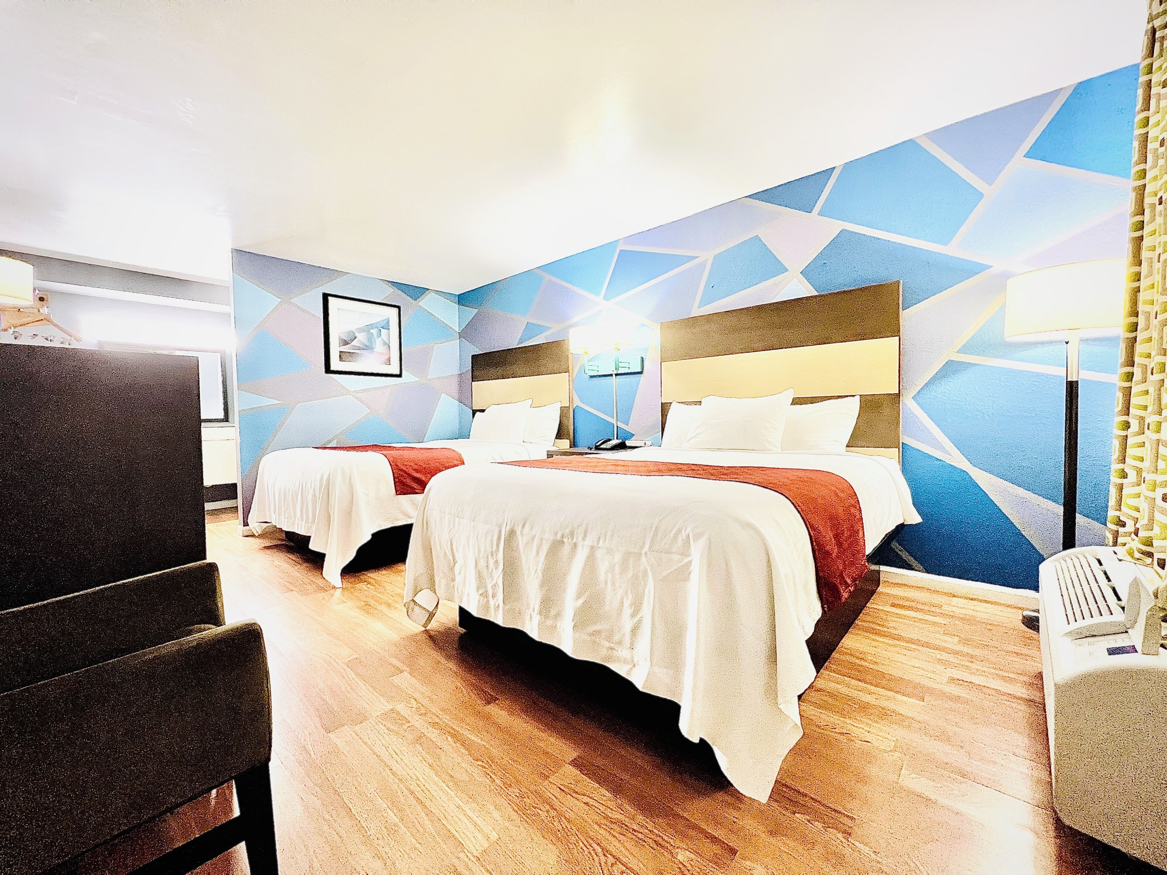 A hotel room with two beds, a desk, and a chair.