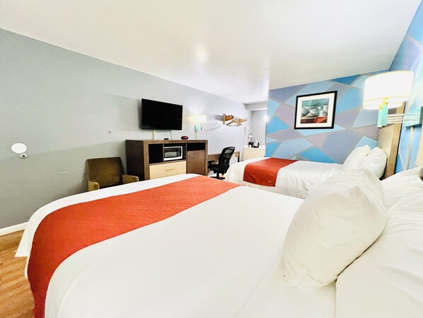 A hotel room with two beds, a desk, a television, and a wall-mounted artwork. - Hometown INN (Berea)