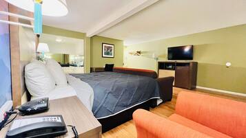 A hotel room with a bed, a desk with a telephone, a television, and a chair.