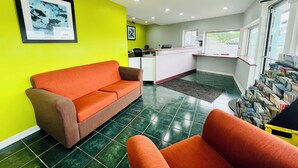 A reception area with a bright green wall, a reception desk, a sofa, and a magazine rack. - Hometown INN (Berea)