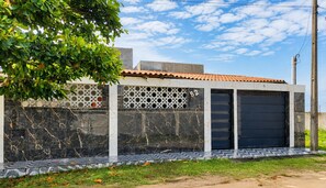 A modern building with a tiled roof, a garage door, and a patterned wall. - Mining House. Perfect for the rest your family deserves. (Nova Viçosa)