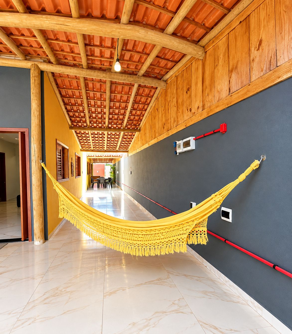 A hallway with a yellow hammock, wooden ceiling, and a grey wall.