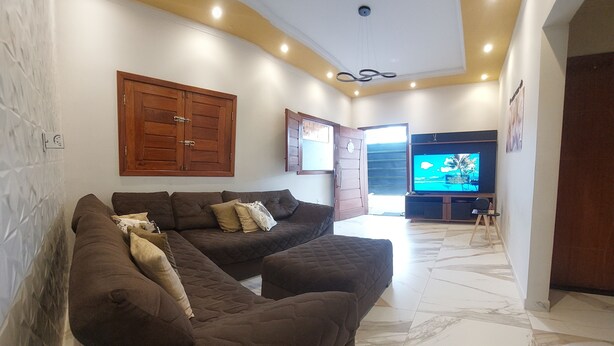 Ein Wohnzimmer mit zwei braunen Sofas, einem Fernseher und einem Holzschrank.