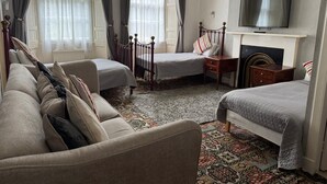 A hotel room with two single beds, a sofa, a television, and a fireplace. - Sofia Rooms (Edinburgh)