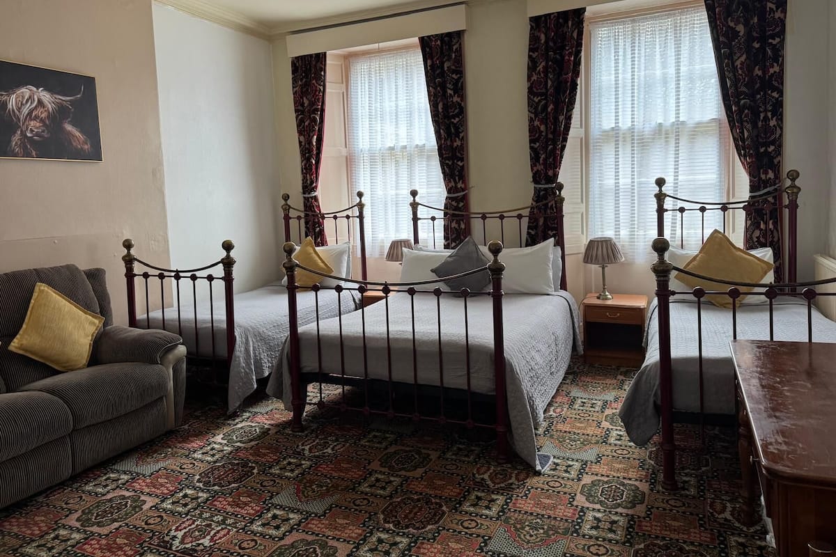 Una habitación tradicional con cama con dosel, un sofá y una mesa.