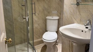 A bathroom with a glass shower enclosure, a toilet, a sink, and a towel rack with towels. - Sofia Rooms (Edinburgh)
