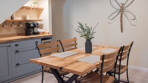Un comedor con una mesa y sillas de madera, un jarrón con una planta y un adorno en la pared.