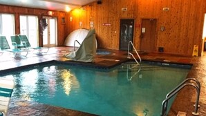 An indoor swimming pool with a wooden wall, a diving board, and a lifeguard chair. - Vista Ridge Retreat at Deer Ridge Mountain Resort (Gatlinburg)