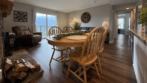 A dining area with a round wooden table, six chairs, and a large wall clock. - Vista Ridge Retreat at Deer Ridge Mountain Resort (Gatlinburg)
