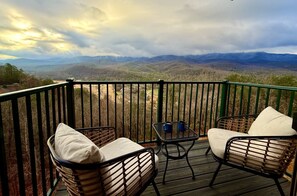 A balcony with wicker chairs and a small table, overlooking a mountainous landscape. - Vista Ridge Retreat at Deer Ridge Mountain Resort (Gatlinburg)