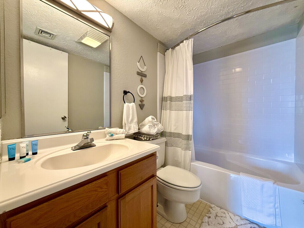 A bathroom with a sink, mirror, toilet, and bathtub.