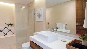 Une salle de bain moderne avec une douche à l’italienne en verre, un lavabo blanc et un grand miroir.