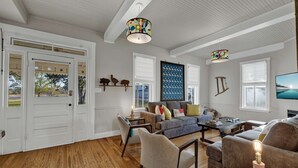Un salon spacieux doté d’un parquet, d’un canapé gris et d’une table basse. On y trouve deux fauteuils, un téléviseur et une lampe décorative.