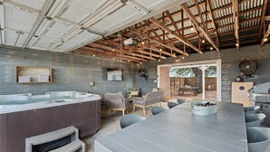 Un espace cuisine extérieur moderne, doté d’un grand bar, de sièges et d’un jacuzzi.
