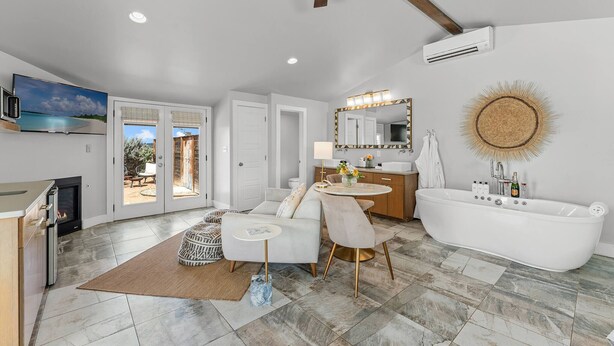 A modern bathroom with a freestanding bathtub, a vanity with a mirror, and a ceiling fan.