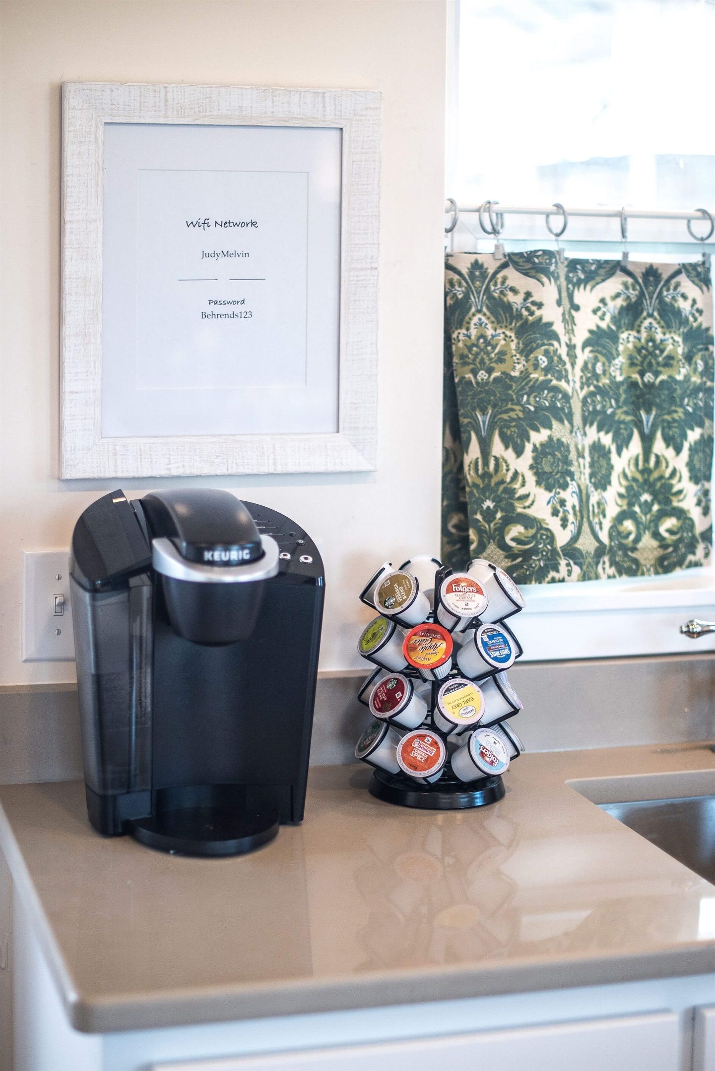 Une machine à café et un présentoir à dosettes de café sont posés sur le plan de travail de la cuisine.