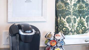 Une machine à café et un présentoir à dosettes de café sont posés sur le plan de travail de la cuisine.