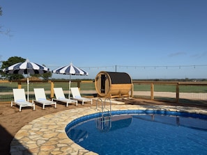 A pool area with lounge chairs and a wooden barrel structure.