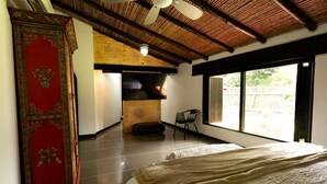 A spacious room with a large bed, a fireplace, and a view through large windows.