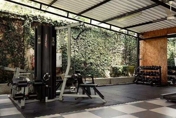 Un gimnasio con una banca de pesas, mancuernas y un rack para sentadillas.