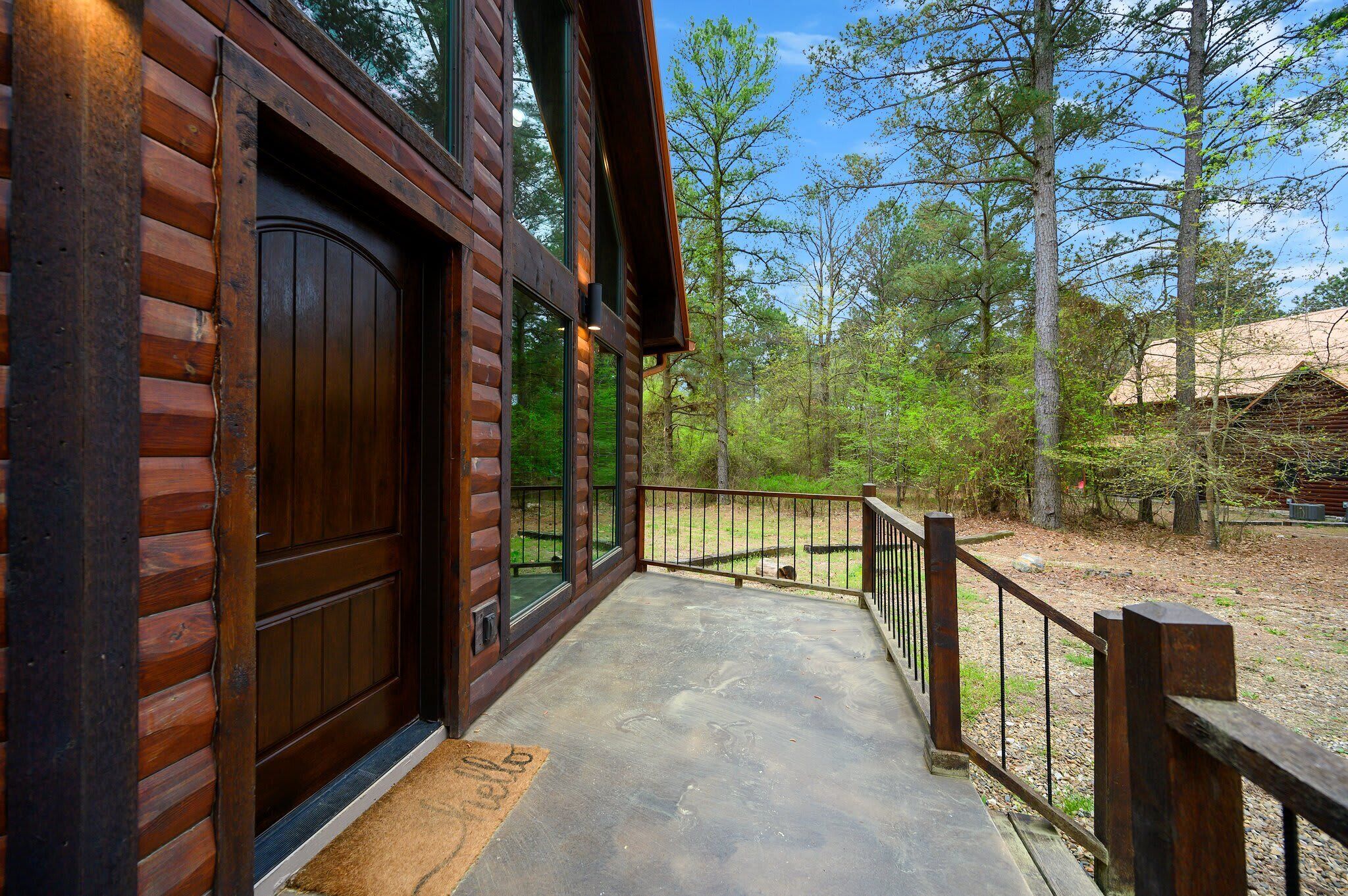 A wooden cabin with a porch and a view of the surrounding forest.
