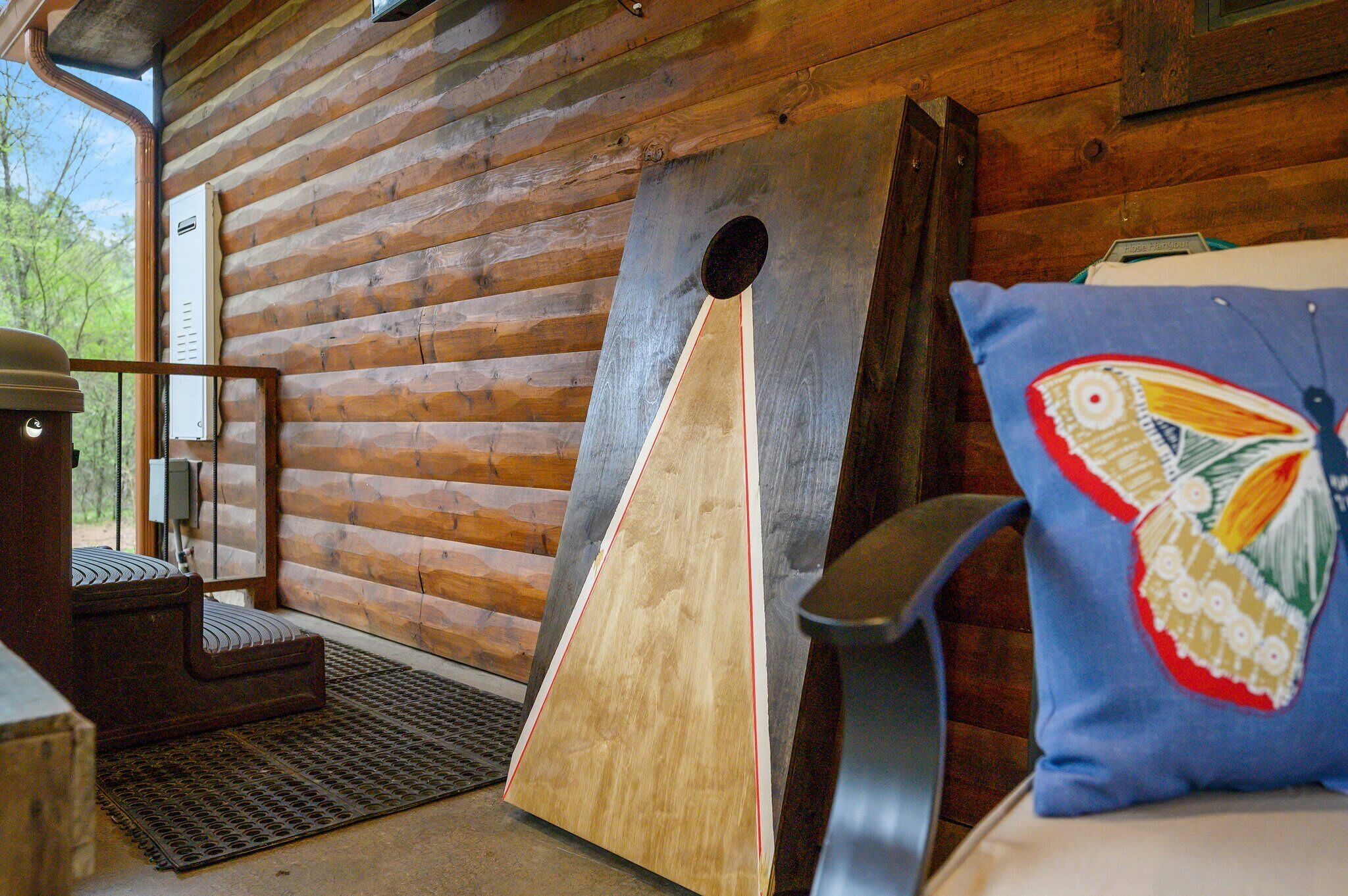 Interno di una baita in legno con una panca di legno, una struttura in legno di grandi dimensioni e un cuscino decorato con un motivo a uccelli.