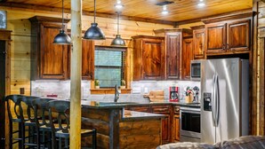 Una cucina rustica con mobili in legno, un frigorifero in acciaio inossidabile e luci a sospensione.