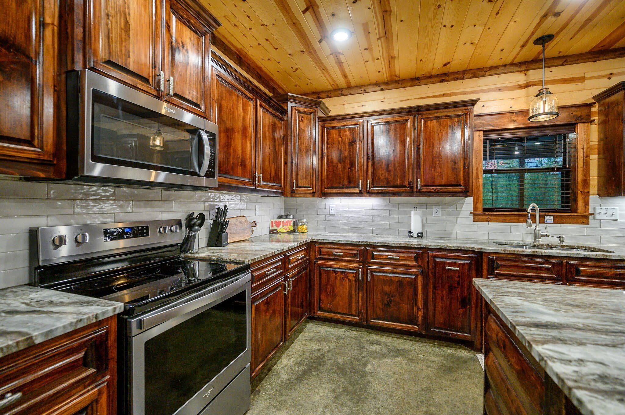 Una cocina con armarios de madera, electrodomésticos de acero inoxidable y encimera de mármol.