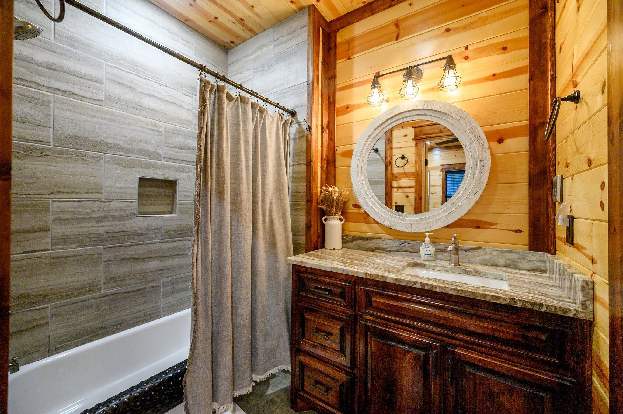 Un baño con tocador de madera, bañera y cortina de ducha.