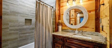 Un baño con tocador de madera, bañera y cortina de ducha.