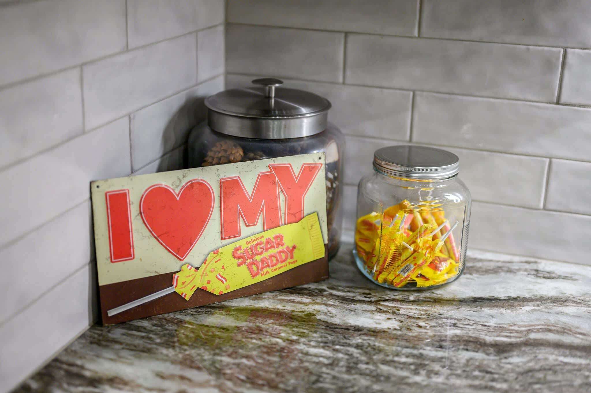 A kitchen counter with a jar of milk caramel popcorn and a sign that reads "I LOVE DADDY."