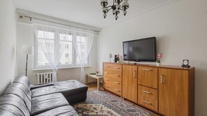 Un salon moderne avec un canapé gris, un meuble en bois et un téléviseur à écran plat.