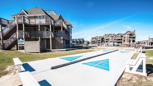 A beachfront property with a wooden deck, a lifeguard tower, and a boardwalk with blue directional arrows.
