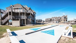 A beachfront property with a wooden deck, a lifeguard tower, and a boardwalk with blue directional arrows. - 1BR Coastal Condo w/ Pool Access (Kitty Hawk)