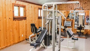 Een sportschool met houten wanden, diverse fitnessapparaten en een bank.