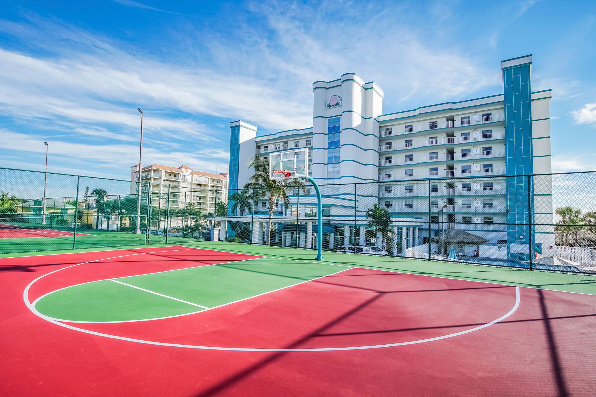 Un hôtel à plusieurs étages avec un terrain de basket devant.