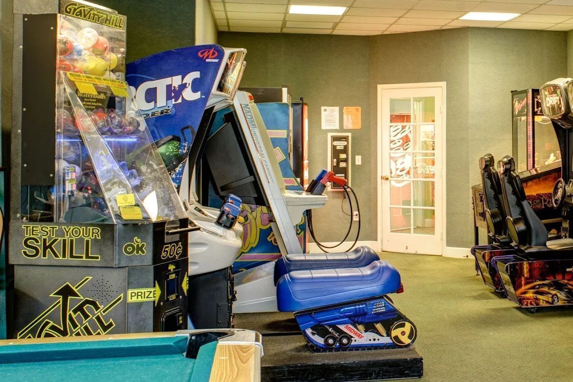 A gaming arcade with various arcade machines, including a racing game and a claw machine.