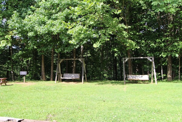 A park with two wooden swings and a picnic table.