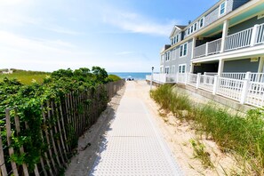 A beachfront walkway with a wooden fence on one side and a building with balconies on the other.